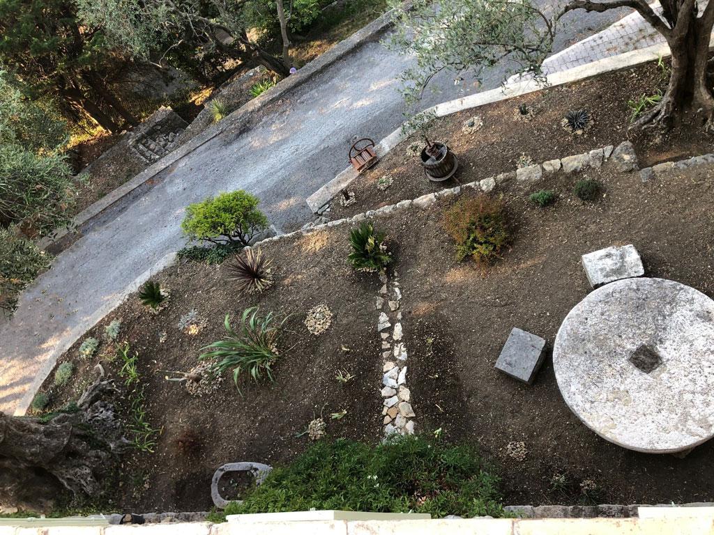 jardin de cactus et plante resistante à la sechresse sur des restanques, décoré d'une meule et d'une presse pour la fabrication d'huile d'olive