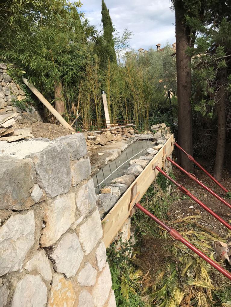 mur en pierre sèche etançonné pour couler du béton